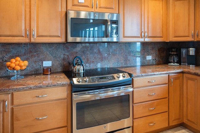 kitchen featuring dark stone counters, backsplash, and stainless steel appliances