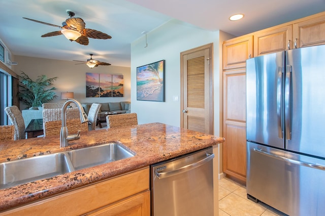 kitchen featuring appliances with stainless steel finishes, light stone countertops, ceiling fan, sink, and light tile flooring