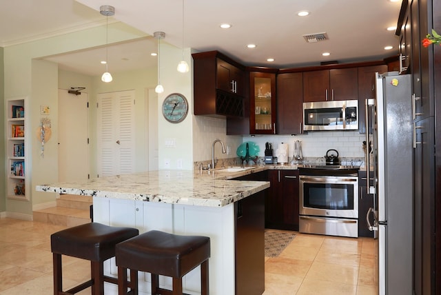 kitchen with sink, appliances with stainless steel finishes, tasteful backsplash, decorative light fixtures, and kitchen peninsula