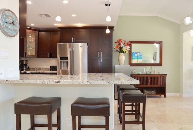 kitchen featuring light stone countertops, a kitchen breakfast bar, ornamental molding, dark brown cabinetry, and stainless steel fridge with ice dispenser