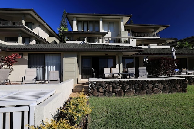 rear view of property with a yard, a patio, and a balcony