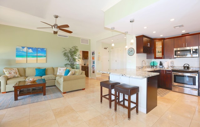 kitchen with sink, hanging light fixtures, tasteful backsplash, a breakfast bar, and appliances with stainless steel finishes