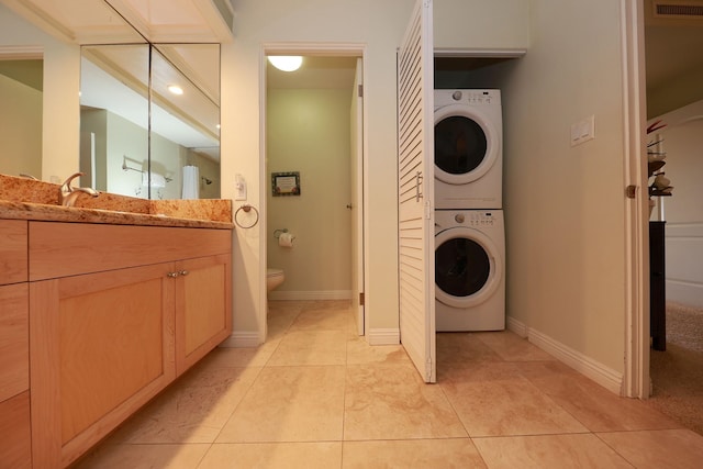 laundry room with light tile patterned flooring and stacked washer / dryer