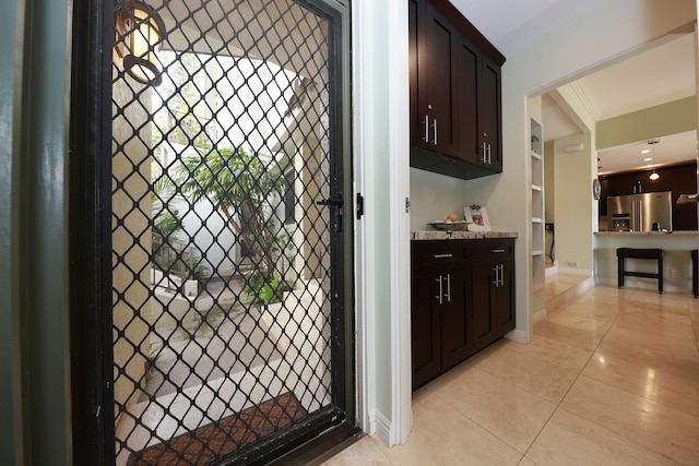 interior space with stainless steel refrigerator with ice dispenser, dark brown cabinetry, and light tile patterned floors