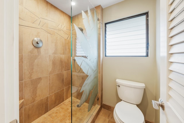 bathroom featuring tiled shower, tile patterned flooring, and toilet