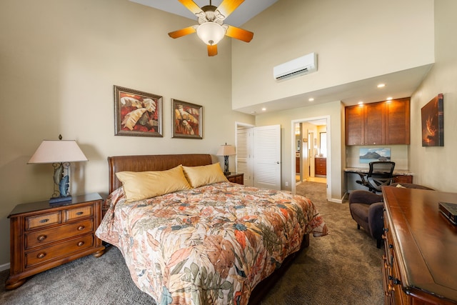 carpeted bedroom featuring a high ceiling, connected bathroom, a wall unit AC, and ceiling fan