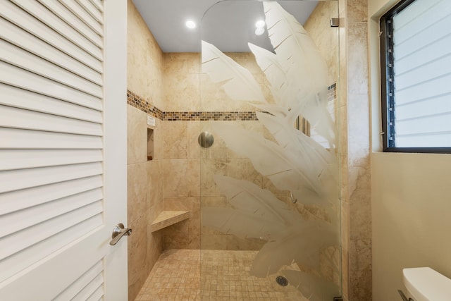 bathroom featuring tiled shower and toilet