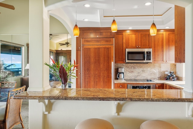 kitchen featuring wall oven, backsplash, decorative light fixtures, a kitchen bar, and black electric stovetop