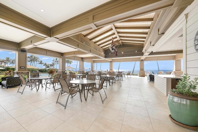 dining area featuring beam ceiling, a water view, and light tile patterned flooring