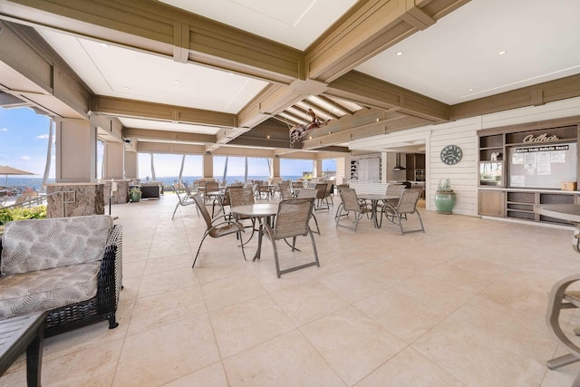 dining room featuring wood walls, light tile patterned floors, and beam ceiling