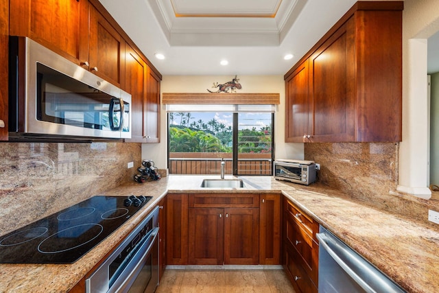 kitchen featuring a raised ceiling, light stone countertops, sink, and appliances with stainless steel finishes