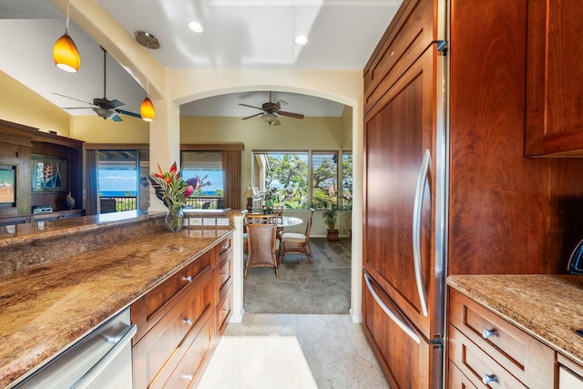 kitchen with stone counters, ceiling fan, light colored carpet, and decorative light fixtures