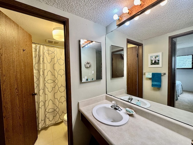 bathroom with vanity, toilet, and a textured ceiling