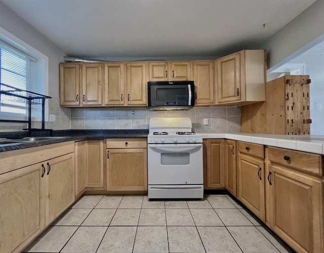 kitchen with light tile patterned flooring, tasteful backsplash, and white range with gas stovetop