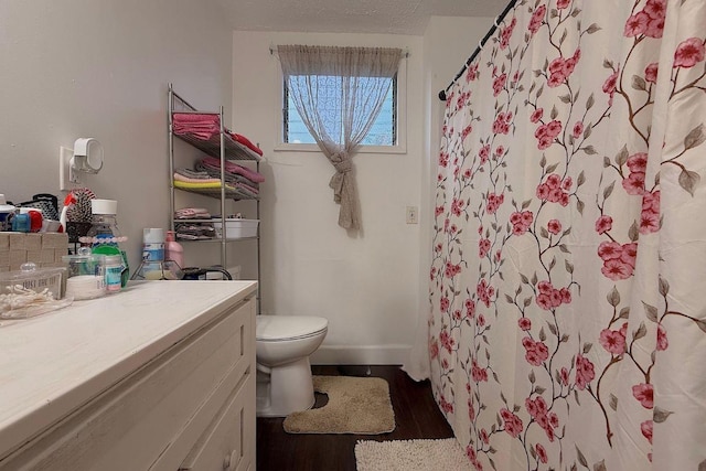 bathroom with vanity, wood-type flooring, a textured ceiling, a shower with curtain, and toilet