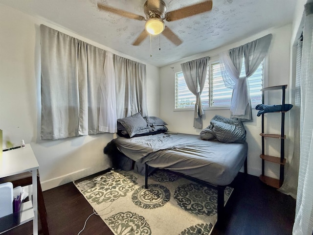 bedroom with multiple windows, wood-type flooring, and ceiling fan