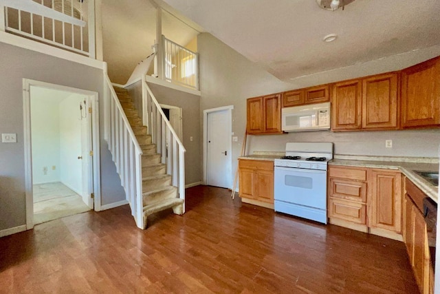 kitchen with white appliances, high vaulted ceiling, and hardwood / wood-style flooring