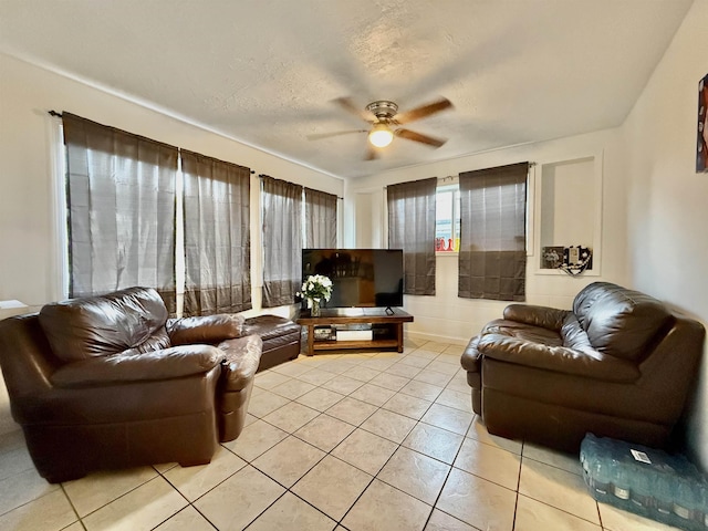 living room featuring light tile patterned floors, a textured ceiling, and ceiling fan