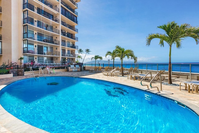 view of swimming pool with a patio area and a water view