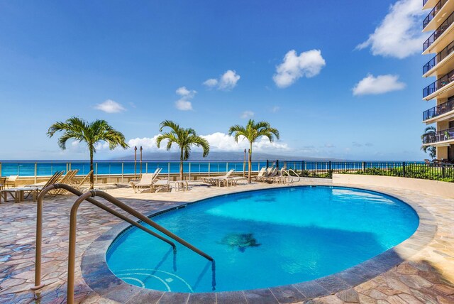 view of swimming pool with a patio area and a water view