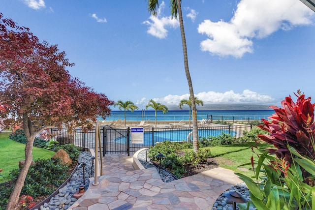 view of swimming pool with a water view and a lawn