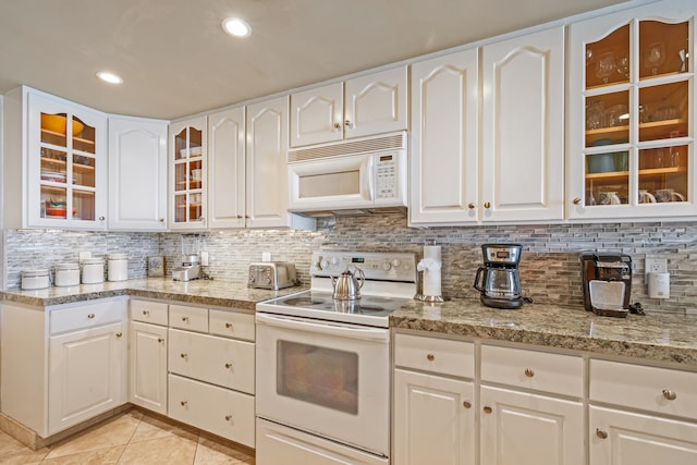 kitchen featuring white cabinets, decorative backsplash, light tile patterned flooring, light stone countertops, and white appliances