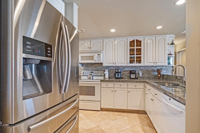 kitchen with decorative backsplash, sink, light tile patterned flooring, white cabinetry, and white appliances