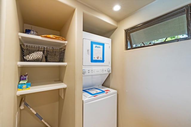 clothes washing area with stacked washing maching and dryer