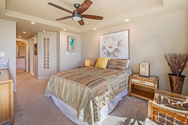 carpeted bedroom with ceiling fan, a raised ceiling, and connected bathroom