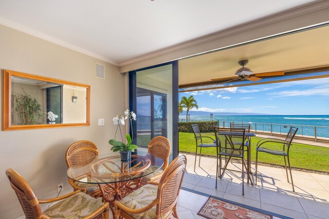 tiled dining area with a wealth of natural light, ceiling fan, a water view, and ornamental molding