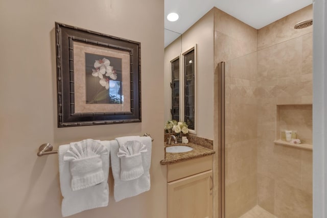 bathroom featuring tiled shower and vanity