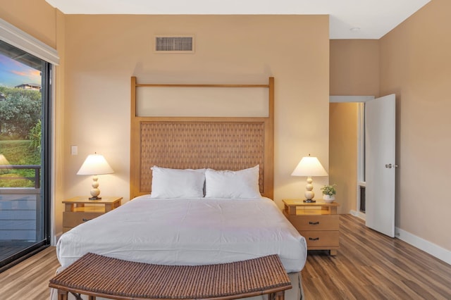 bedroom featuring multiple windows, wood finished floors, visible vents, and baseboards