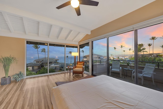 bedroom featuring lofted ceiling with beams, access to outside, multiple windows, and wood finished floors