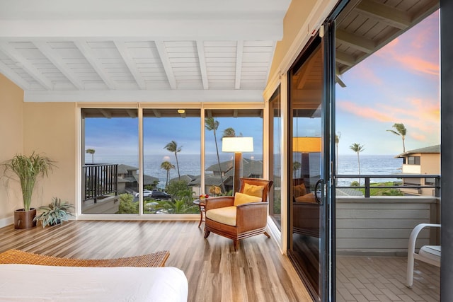 interior space featuring access to outside, a water view, vaulted ceiling with beams, and wood finished floors