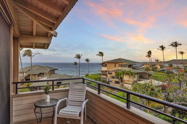 balcony at dusk featuring a water view