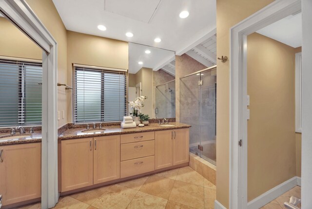 bathroom featuring a tile shower, double vanity, and a sink