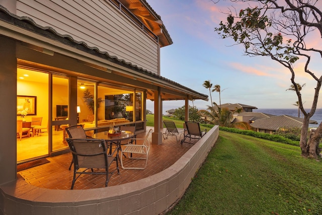 patio terrace at dusk featuring a yard