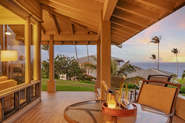 patio terrace at dusk with a water view and a lawn