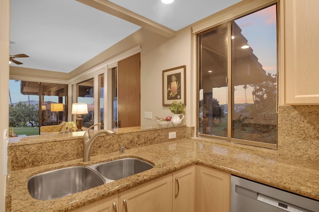 kitchen with light stone counters, a sink, a ceiling fan, stainless steel dishwasher, and backsplash