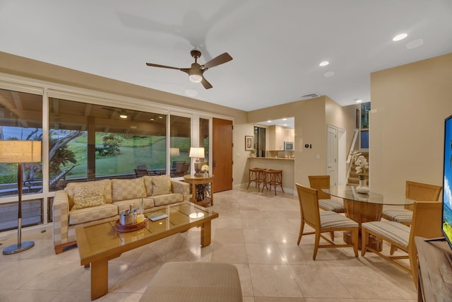 living area featuring light tile patterned floors, baseboards, a ceiling fan, stairway, and recessed lighting