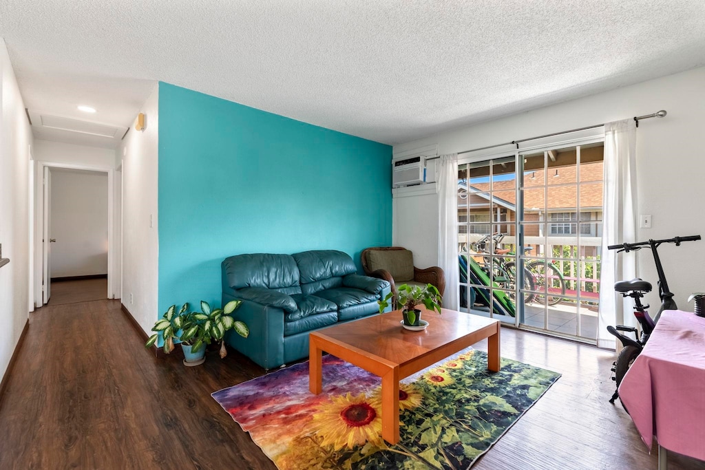 140 Uwapo Rd Unit 31-202, Kihei, HI 96753 - living room featuring a wall mounted AC, a textured ceiling, and wood finished floors