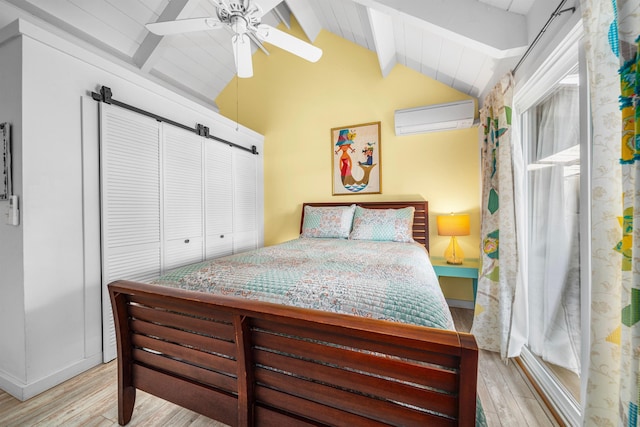 bedroom featuring ceiling fan, light hardwood / wood-style floors, a wall unit AC, and lofted ceiling with beams