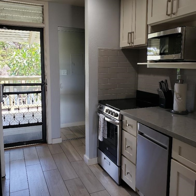 kitchen featuring white cabinets, backsplash, light hardwood / wood-style floors, and appliances with stainless steel finishes