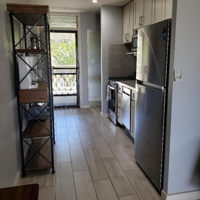 kitchen with appliances with stainless steel finishes, backsplash, light hardwood / wood-style floors, and white cabinets