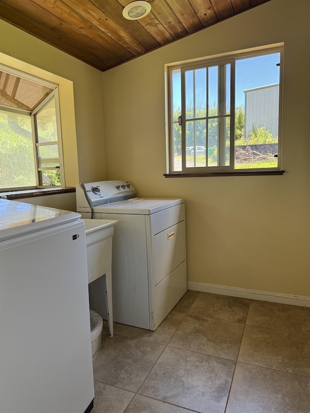 clothes washing area featuring laundry area, washer and clothes dryer, wood ceiling, and a wealth of natural light