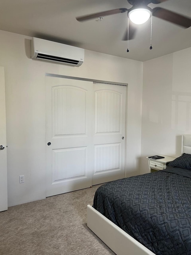 bedroom with a closet, light colored carpet, a wall unit AC, and ceiling fan