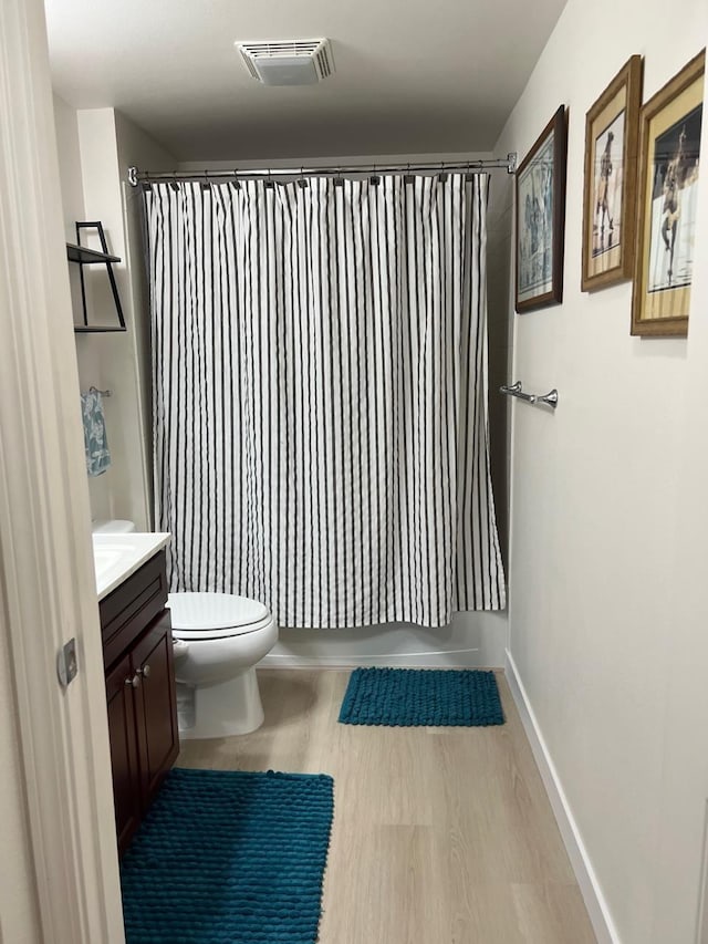 full bathroom featuring hardwood / wood-style flooring, vanity, toilet, and shower / bath combo with shower curtain