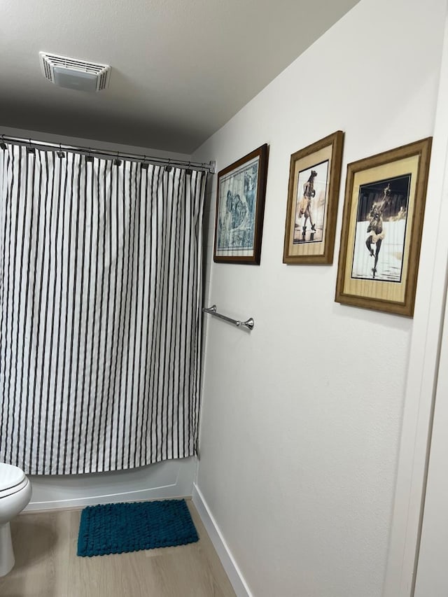 bathroom featuring hardwood / wood-style flooring, toilet, and shower / tub combo