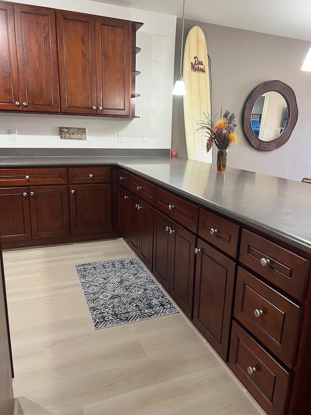 kitchen with kitchen peninsula, pendant lighting, and light wood-type flooring