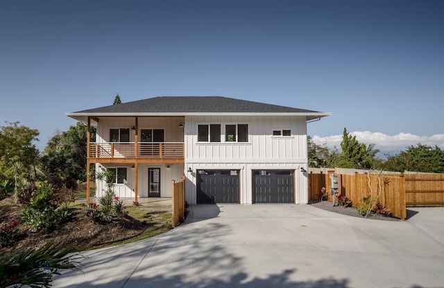 view of front of house featuring driveway, a shingled roof, a balcony, fence, and board and batten siding